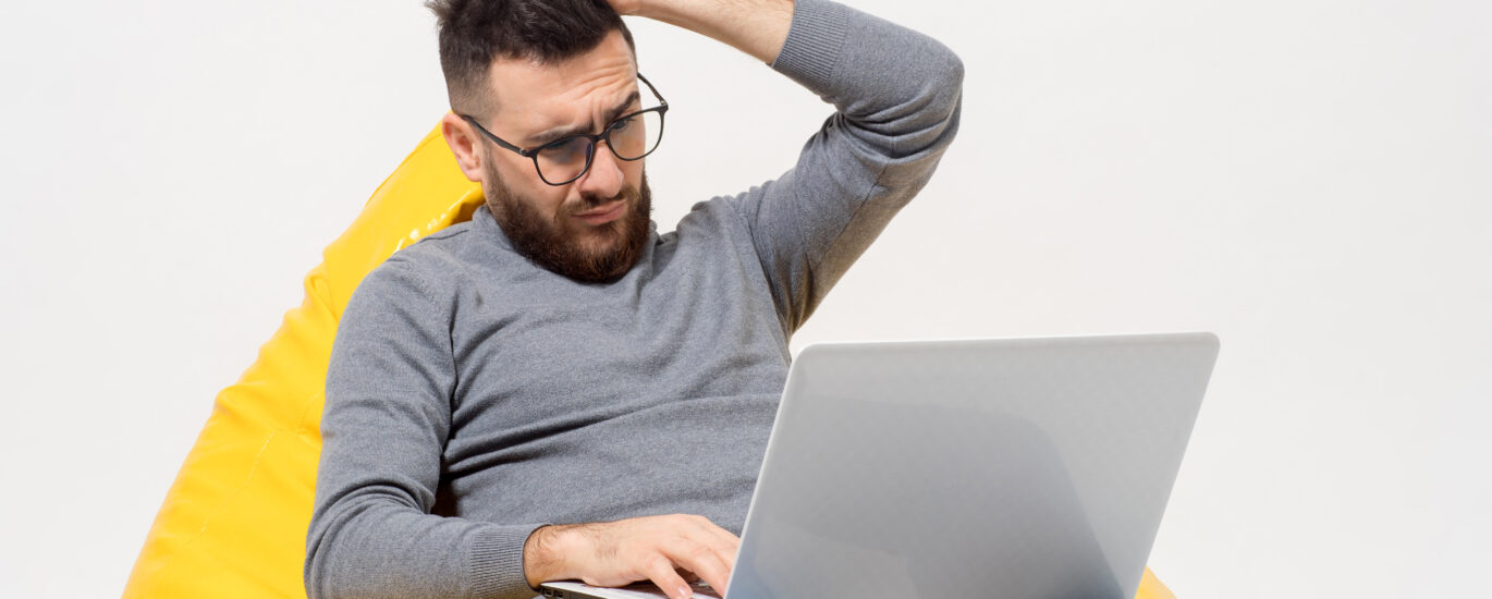 Person troubleshooting a Lenovo laptop that won’t turn on, checking the power button and charger connection on a desk.