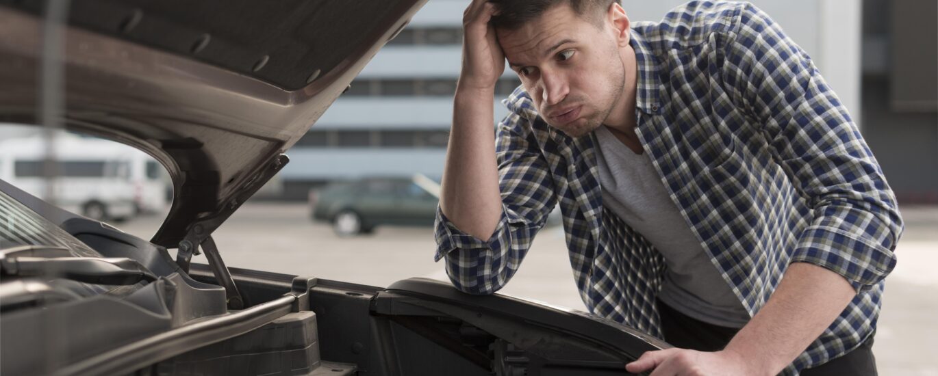 A mechanic testing a car battery with a multimeter to explain how long car batteries last and when to replace them.