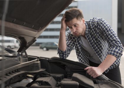 A mechanic testing a car battery with a multimeter to explain how long car batteries last and when to replace them.