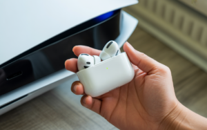 Alt text: A gamer pairing Apple AirPods to a PS5 using a Bluetooth adapter, smart TV, and PS Remote Play app for wireless audio.